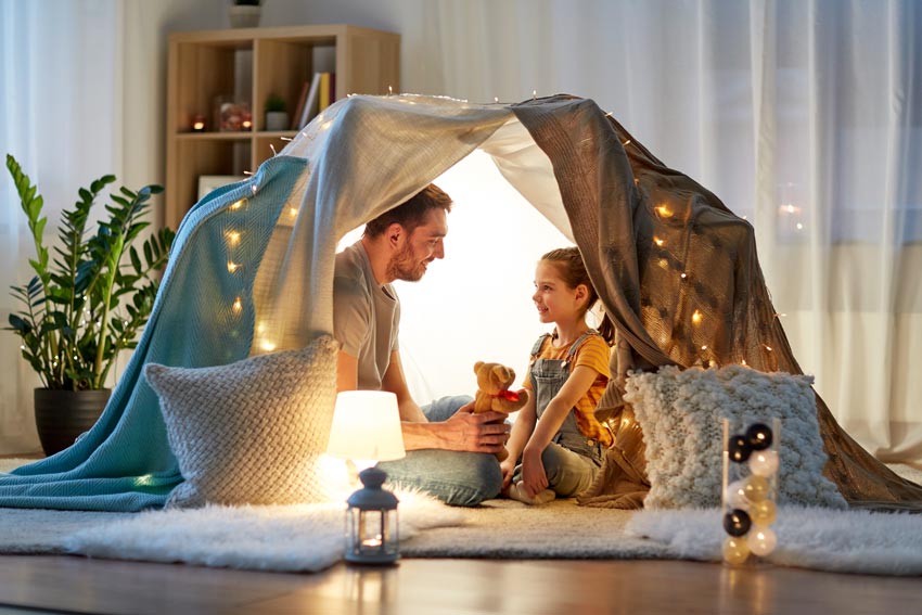 Dad and daughter sitting in a tent in the family room